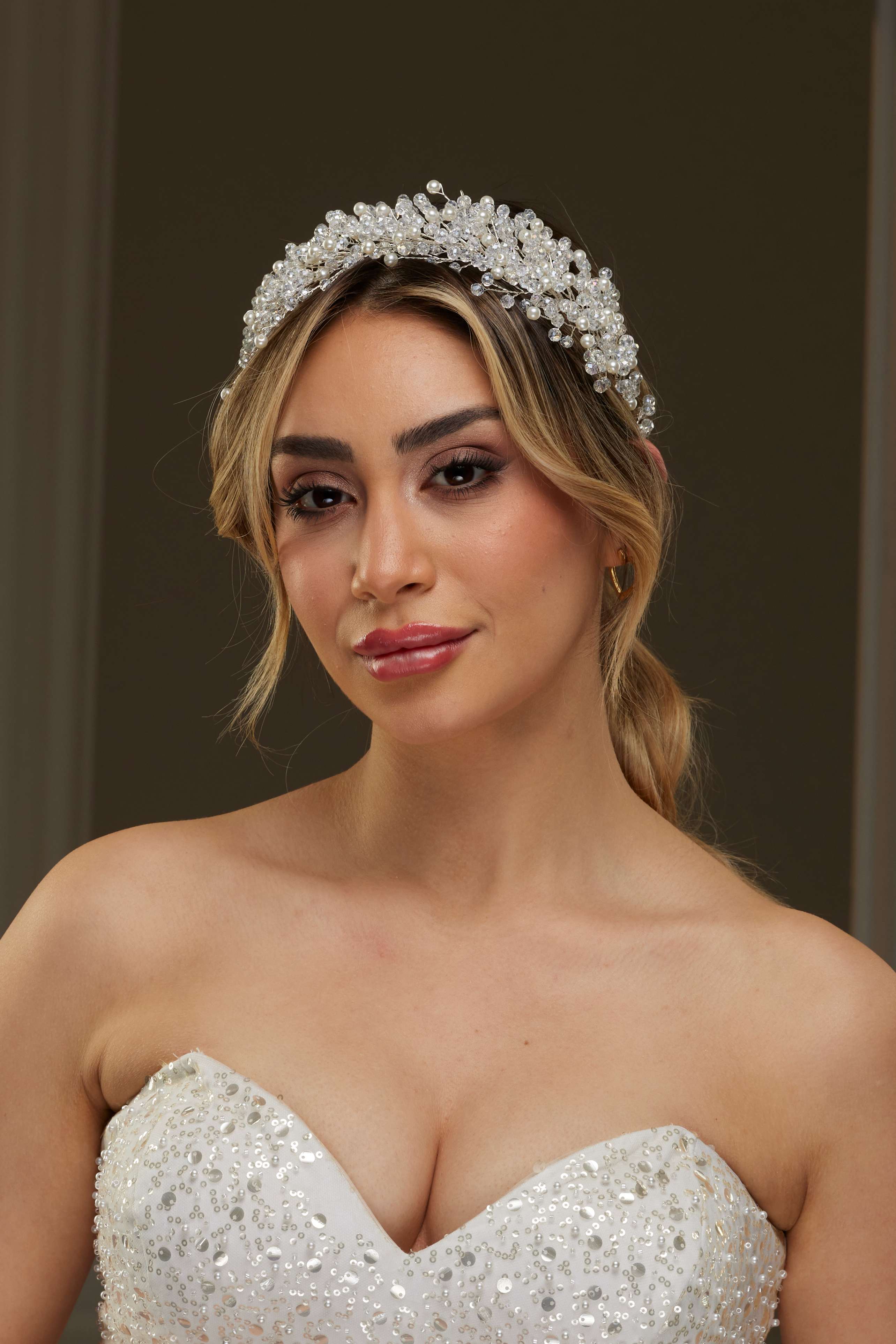 Beyaz kristal ve boncuk detaylı büyük gelin tacı – sarı meşeli topuzda önden görünüm, beyaz straplez boncuklu gelinlik ile uyumlu görkemli gelin saç aksesuarı