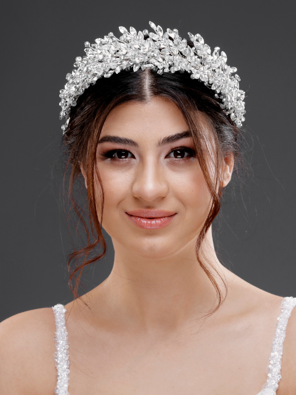 Gümüş kristal yaprak formlu zarif gelin tacı – dalgalı açık saçta ön görünüm, beyaz dantel gelinlik ile uyumlu klasik ve sofistike nikah saç aksesuarı