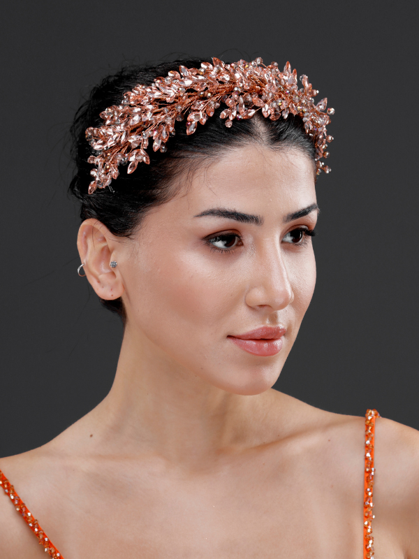 Metalik rose gold kristal yaprak formlu zarif gelin tacı – toplu düz saçta ¾ görünüm, turuncu taşlı elbise ile uyumlu ışıltılı ve modern gelin saç aksesuarı