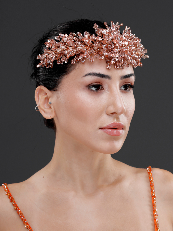 Rose gold metalik yoğun kristal yüksek form gelin tacı – topuz saçta ¾ görünüm, turuncu boncuklu elbise ile uyumlu çarpıcı ve modern özel gece saç aksesuarı