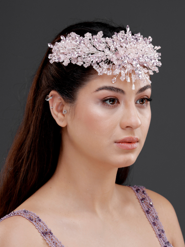 Pembe yoğun kristal yüksek form gelin tacı – düz açık saçta ¾ görünüm, lila askılı elbise ile uyumlu romantik ve görkemli gelin saç aksesuarı