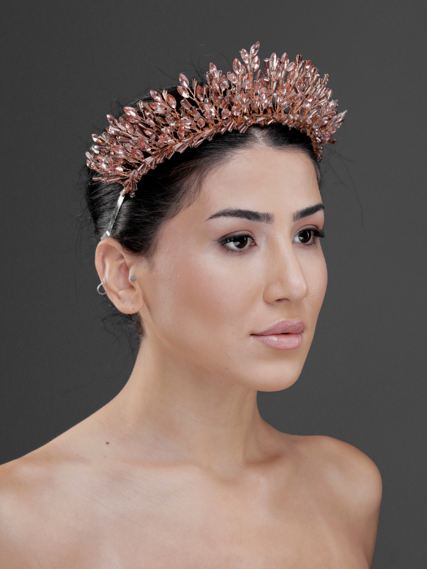 Metalik rose gold kristal gösterişli gelin tacı – koyu saçta yan görünüm, ışıltılı bakır tonlu yaprak motifli zarif saç tacı düğün ve özel davetler için